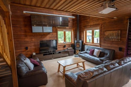 a living room with leather furniture and a flat screen tv at Pine Tree Lodge - Pentney Lakes in Pentney