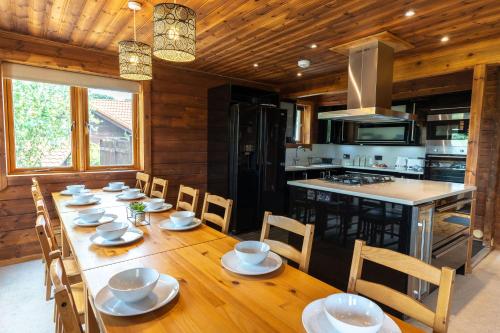 a dining room with a long table and a kitchen at Pine Tree Lodge - Pentney Lakes in Pentney
