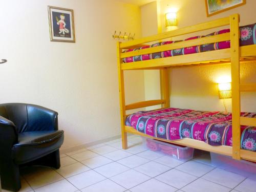 Un dormitorio con una litera y una silla. en Lagon 173 - Maison de Vacances - 3 Chambres, en Gruissan
