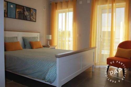 Un dormitorio con una cama grande y una silla roja. en MAR I TERRA, en Olhão