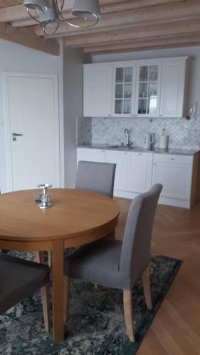 a kitchen with a wooden table and two chairs and a sink at Apartament Morskie Wzgórze II in Mechelinki