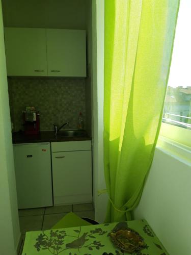 una cocina con cortina verde y fregadero en Rooms and Apartment Stambuk, en Split