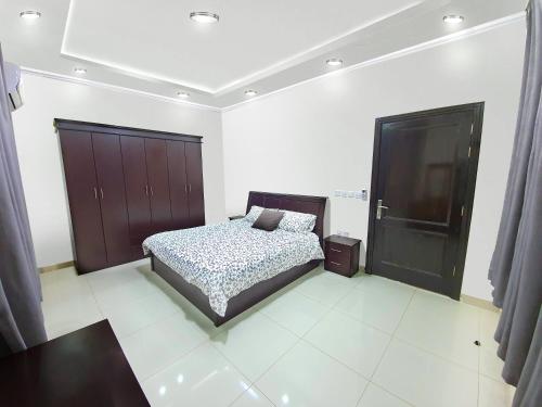 a bedroom with a bed and a black cabinet at Al Estraha Al Raqia Vila in Al Hada