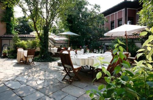a patio with tables and chairs and umbrellas at Old Legends Hotel in Plovdiv