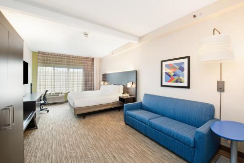 Holiday Inn Express - Delafield, an IHG Hotel في Delafield: غرفة في الفندق مع أريكة زرقاء وسرير