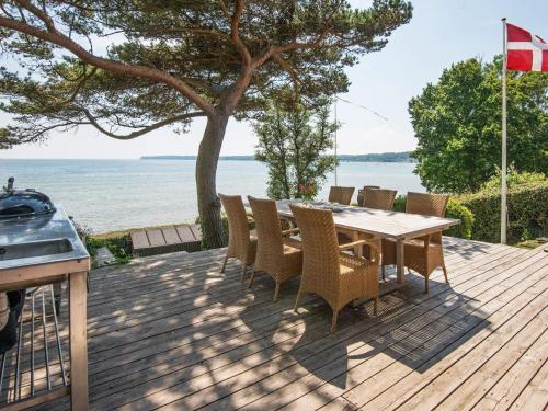 a wooden deck with a table and chairs and the ocean at 6 person holiday home in Bjert in Sønder Bjert