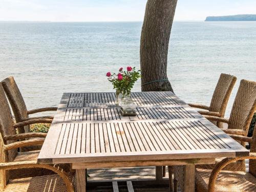 een houten tafel met een vaas met bloemen op het strand bij 6 person holiday home in Bjert in Sønder Bjert