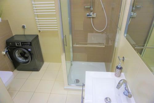 a bathroom with a shower and a sink and a washing machine at Usedom-Apartment im Haus Feniks in Świnoujście