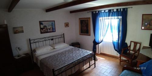 1 dormitorio con 1 cama y una ventana con cortinas azules en Il Borgo 38 en Scapoli