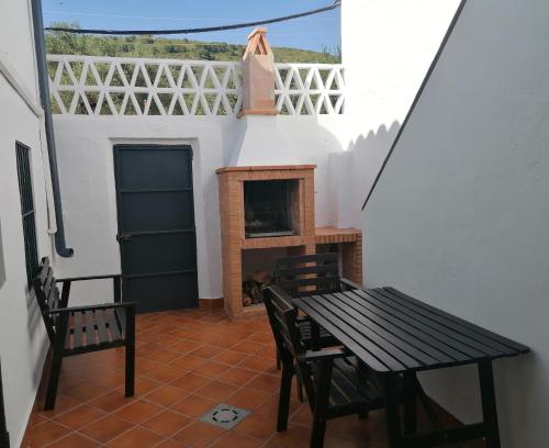 un patio con mesa, sillas y chimenea en Casa Rural Ventanas a la Sierra, en Higuera de la Sierra