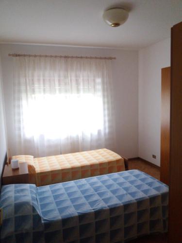 1 dormitorio con 1 cama frente a una ventana en Appartamento con giardino Gemona, en Gemona del Friuli