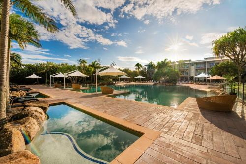 a beach with a pool and palm trees at Peppers Salt Resort & Spa in Kingscliff
