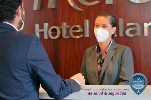 a woman wearing a mask shaking hands with a man at Mercure Alameda Quito in Quito
