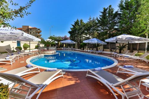 a swimming pool with lounge chairs and umbrellas at Hotel Max Prestige in Budva