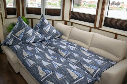 a couch in a room with a quilt and pillows at Island-dreams Hausboot Cecilie in Schleswig