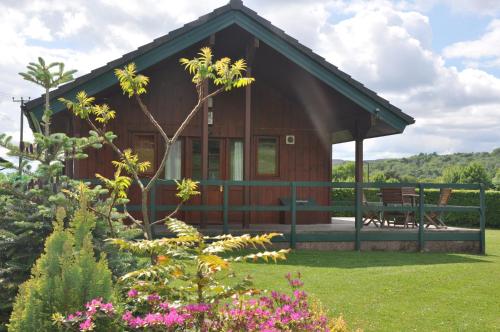 a small wooden cabin with a porch and some flowers at Wellsfield Farm Holiday Lodges in Stirling