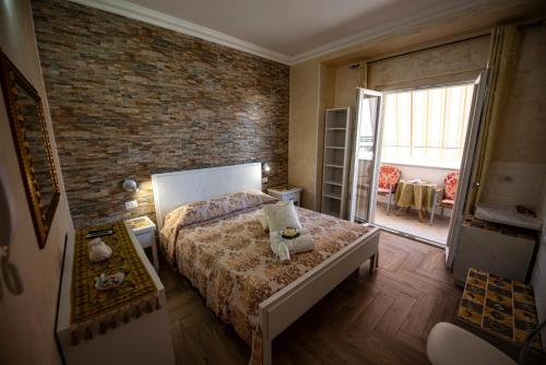 1 dormitorio con cama y pared de ladrillo en La Perla Del Tirreno, en Tropea