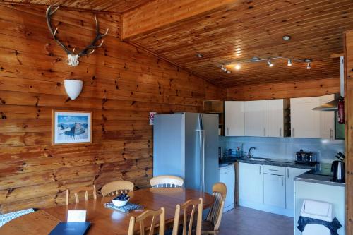 a kitchen with wooden walls and a table and chairs at Woodland Gean Lodge in Killin
