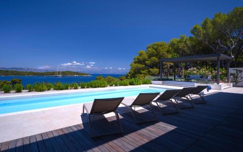 a pool with chairs and a gazebo next to the water at Villa Eola Hvar in Jelsa
