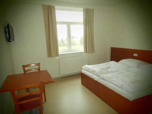 a bedroom with a bed and a table and a window at Sport Hotel České Budějovice in České Budějovice