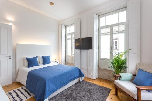 Dormitorio blanco con cama azul y sofá en Alegria 283, en Oporto