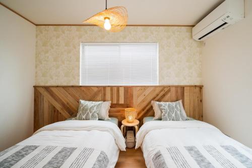 sypialnia z 2 łóżkami i oknem w obiekcie Casa Viaggio w mieście Uruma