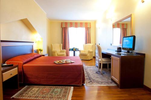 Pokój hotelowy z łóżkiem i biurkiem z telewizorem w obiekcie Hotel Grillo w mieście Assemini