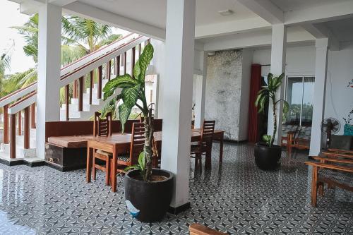 a dining room with a table and potted plants at Sunset View Beach Hotel in Arugam Bay