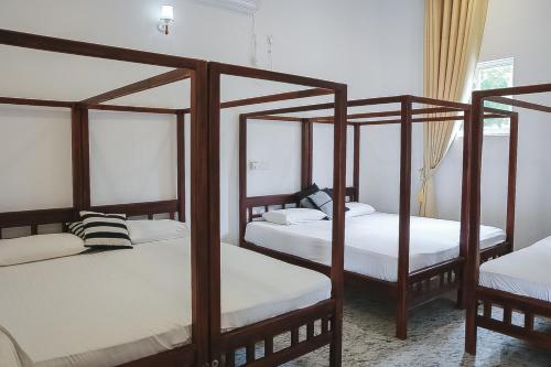a bedroom with four bunk beds with white sheets at Sunset View Beach Hotel in Arugam Bay