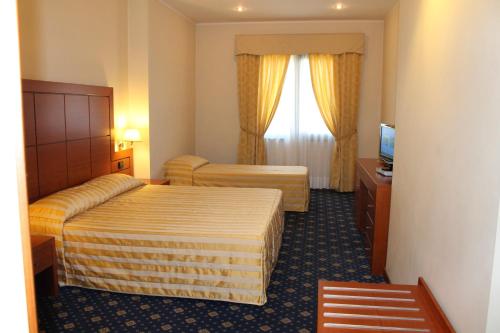 a hotel room with two beds and a television at Hotel Grillo in Assemini
