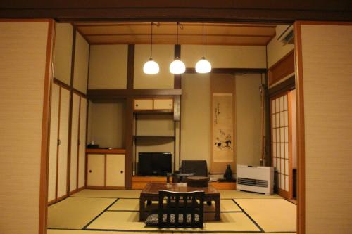 sala de estar con mesa, sillas y luces en Historical Ryokan SENYUKAN, en Ōwani