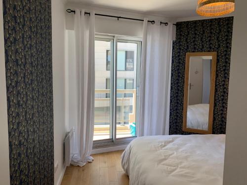 a bedroom with a bed and a large window at La Baule Family in La Baule