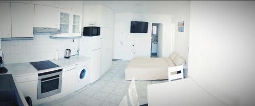 a kitchen with white cabinets and a couch in it at Domus Dulcis Domus in Hersonissos