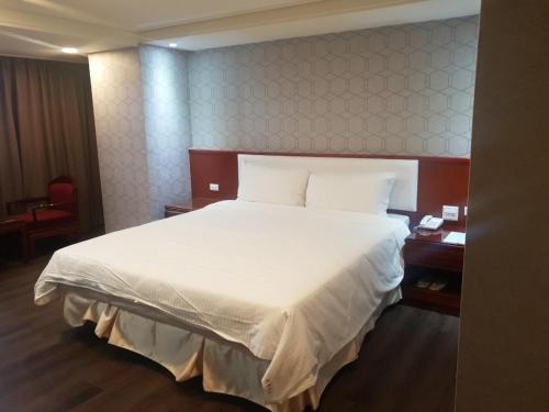 a bedroom with a large bed with white sheets at Chuan Fu Hotel in Fengyuan