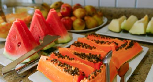 a table topped with plates of food with fruit at Colonial Hotel in Ilhabela