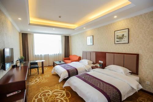 a hotel room with two beds and a desk at New Knight Royal Hotel Airport and International Resort in Shanghai