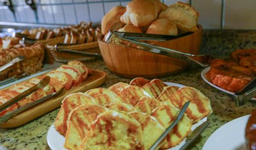 a table topped with plates of bread and pastries at Colonial Hotel in Ilhabela