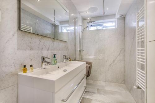 een witte badkamer met een wastafel en een douche bij Artis Plantage Apartment in Amsterdam