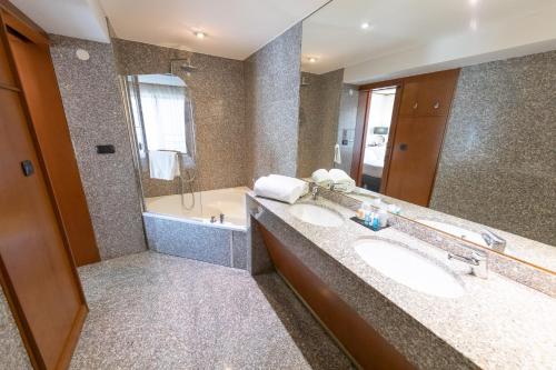 a bathroom with a tub, sink and mirror at Goldstar Apartments & Suites in Nice