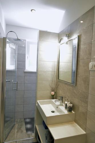 uma casa de banho com um lavatório e um chuveiro com um espelho. em Villa Perla with swimming pool, Lovran - Opatija em Lovran
