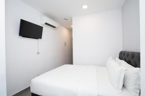 a white bedroom with a bed and a tv at B Lot Hotel in Kuala Lumpur