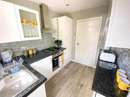 a small kitchen with a sink and a stove at New Contractor House Near LLA Airport & M1 in Luton