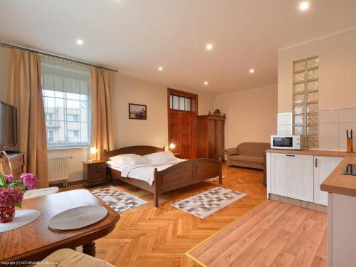 Una sala de estar con una cama y una cocina. en Apartamenty Słupskie, en Słupsk