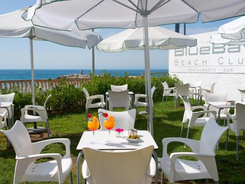 a group of tables and chairs under umbrellas at a beach club at BlueBay Banús in Marbella