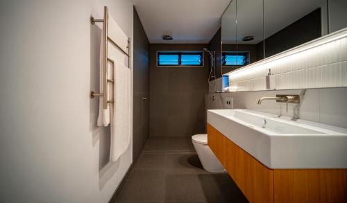 a bathroom with a white sink and a toilet at Aria Port Douglas Villas - Villa 1 in Port Douglas