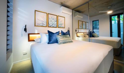 a bedroom with two beds with blue pillows at Aria Port Douglas Villas - Villa 1 in Port Douglas