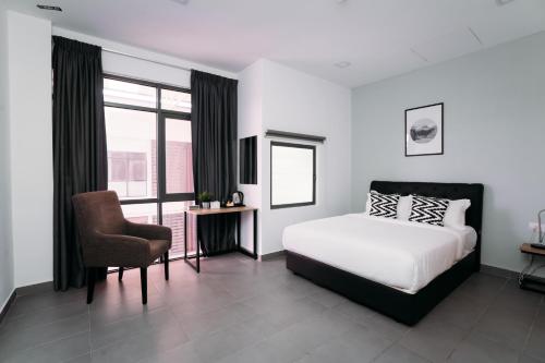 a bedroom with a bed and a chair and a window at B Lot Hotel in Kuala Lumpur