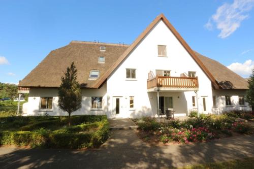 a large white house with a porch and a balcony at Fewo 2 Stueven im Reetdachhaus Fewo cc in Kolpinsee