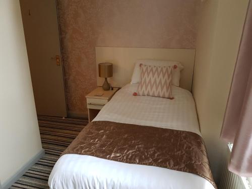 a small bedroom with a bed with a pink pillow at 74 Belgravia in Torquay