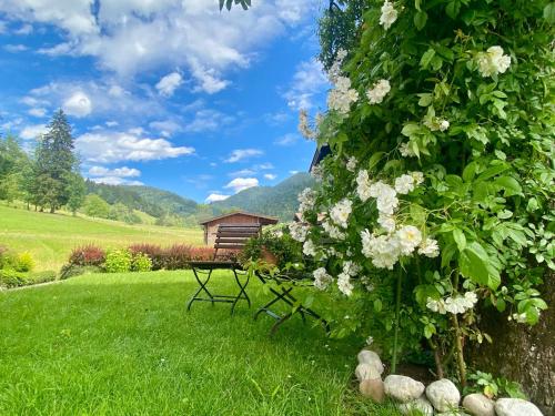 a picnic table in the grass with a bush with flowers at Haus Leiter in Reit im Winkl